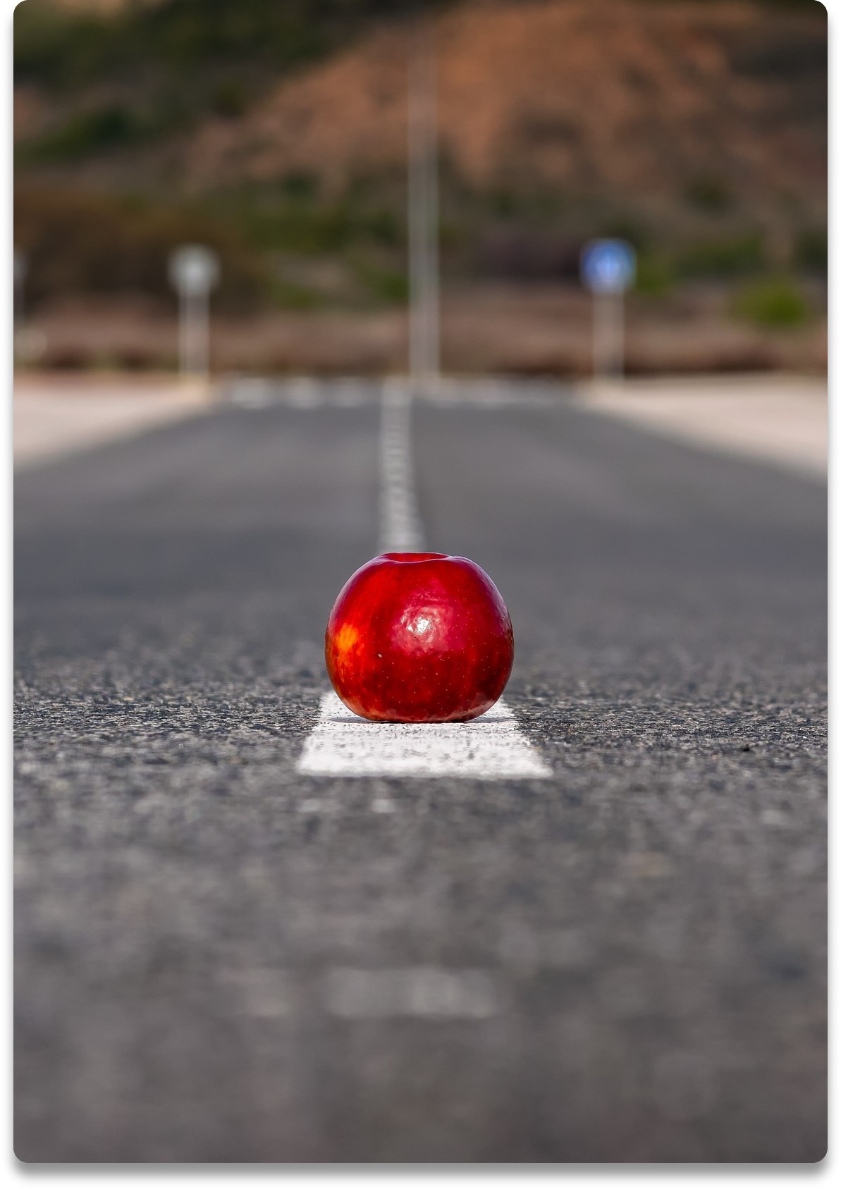 Ett rött äpple på mitt-strecket av en vägbana. Bilden symboliserar möjligheter.